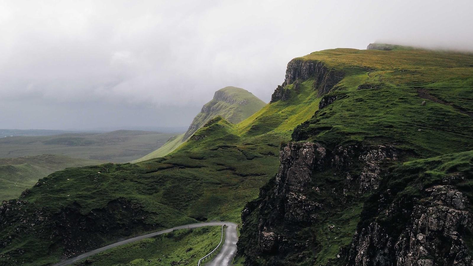 Winding road through lush green misty highland hills